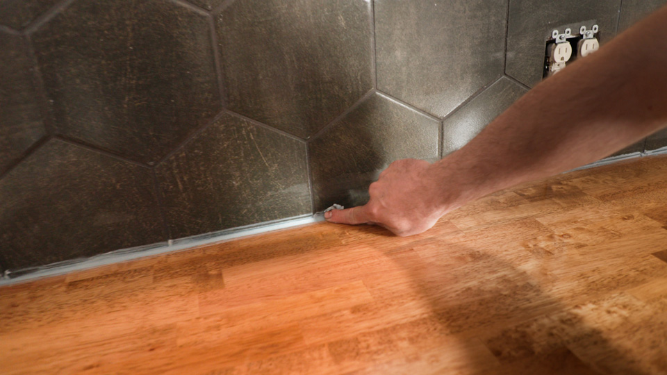 running over the bead of caulk with a finger to smooth it